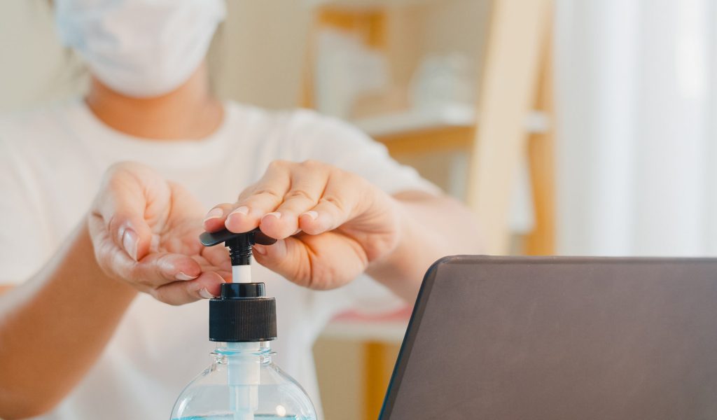 Asian woman using alcohol gel hand sanitizer wash hand before open laptop for protect coronavirus. Female push alcohol to clean for hygiene when social distancing stay at home and self quarantine time